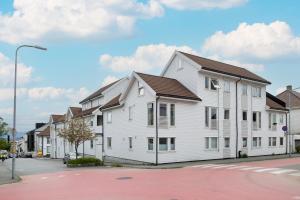 a white building with a brown roof on a street at Central top floor apartment in Stavanger