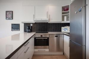 una cocina con armarios blancos y electrodomésticos de acero inoxidable en Central top floor apartment, en Stavanger