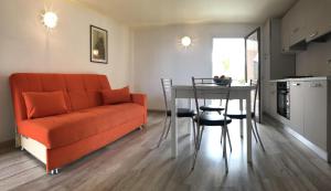 a living room with an orange couch and a table at Sardegna Beach Cala Reale in Santa Marinella