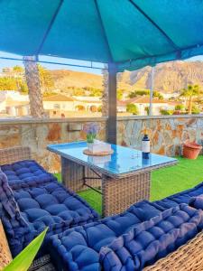 eine Terrasse mit einem Tisch und einem blauen Sonnenschirm in der Unterkunft The perfect place to relax Bedroom with hot tub, beautiful tropical garden area. Bbq and big open spaces through all the house.It is located in a quiet place, but still 5 min away from the touristic Puerto Rico and walking distance from the beach in Mogán