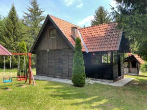 ein Haus mit rotem Dach und Schaukel in der Unterkunft Vikendica na Sokolini in Gornja Koprivna