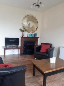a living room with two chairs and a table and a tv at Kilkee Bay Apartments in Kilkee