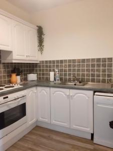 a kitchen with white cabinets and a sink at Kilkee Bay Apartments in Kilkee