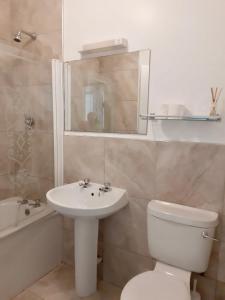 a bathroom with a sink and a toilet and a mirror at Kilkee Bay Apartments in Kilkee