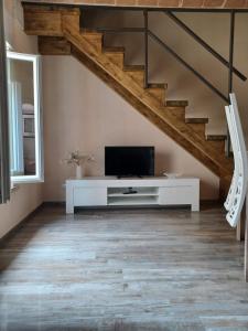 a living room with a tv and a staircase at Dimora alla Chiesa Diruta in Grottole