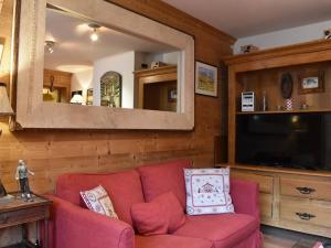 a living room with a red couch and a large mirror at Appartement cosy avec cheminée, terrasse et parking, proche pistes et commerces - Méribel - FR-1-180-552 in Méribel