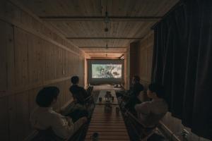 un grupo de personas sentadas en una habitación viendo una televisión en Noasobi Lodge 202- Vacation STAY 23084v, en Arao
