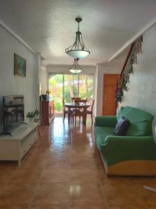 Bungalow muy cerca de la playa في سانتا بولا: غرفة معيشة مع أريكة خضراء وطاولة