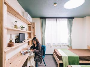 a woman sitting at a table in a hotel room at Noasobi Lodge 203- Vacation STAY 23343v in Arao