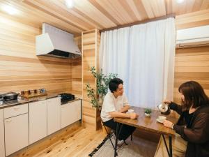 zwei Personen sitzen an einem Tisch in einer Küche in der Unterkunft Noasobi Lodge 203- Vacation STAY 23343v in Arao