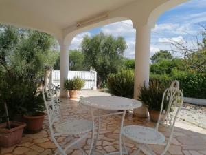 eine Terrasse mit zwei weißen Stühlen und einem Tisch in der Unterkunft Villa Floris giardino AIRCON WIFI Parcheggio in Ostuni