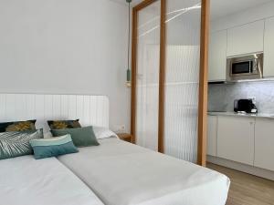 ein großes weißes Bett in einem Zimmer mit Küche in der Unterkunft Apartamentos Succo in Plasencia