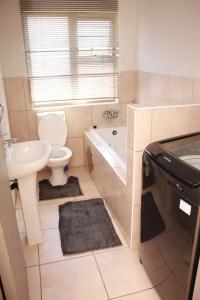 a bathroom with a sink and a toilet and a tub at 43 Home self Catering with backup power in eMalahleni