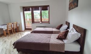 een slaapkamer met 2 bedden, een tafel en een raam bij Noclegi Kalniczka in Tarnawa Dolna