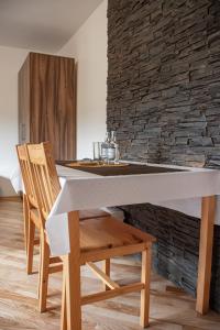 mesa de comedor con 2 sillas y pared de piedra en Noclegi Kalniczka en Tarnawa Dolna