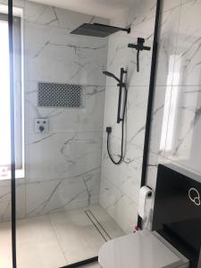 a bathroom with a shower with white marble walls at Studio calme-équipements haut de gamme in Sarreguemines