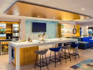 a kitchen with a large counter with stools around it at Mercure Rouen Centre Cathédrale in Rouen