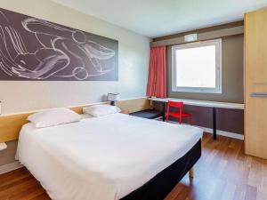 a bedroom with a large bed and a red chair at ibis Strasbourg Centre Historique in Strasbourg