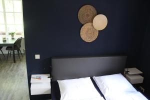 Un dormitorio con una pared negra con una cama y dos sombreros en Erve Praestinck en Stegeren