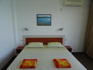 1 dormitorio con 1 cama con 2 almohadas en Dobrevi Guest House en Primorsko