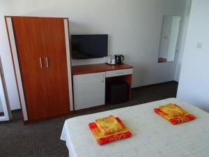 プリモルスコにあるDobrevi Guest Houseのベッド、テレビ、キャビネットが備わる客室です。