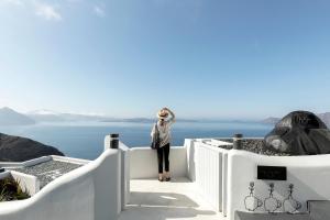a woman standing on a ledge looking out over the ocean at Hom Santorini in Oia
