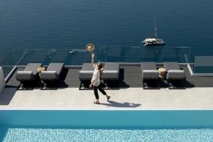 a woman is playing with a hat on a boat at Hom Santorini in Oia