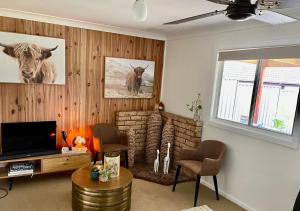 uma sala de estar com televisão e uma vaca na parede em Quirky little 2 bedroom in quiet cul-de-sac em Kempsey