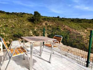 a table and chairs on a patio with a hill at Casas y Cuevas El Solins in Las Casicas
