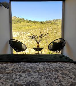 a bedroom with two chairs and a large window at Casas y Cuevas El Solins in Las Casicas