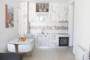 a kitchen with white cabinets and a table and a sink at Apartment Sunset in Kotor