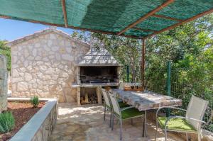 a patio with a table and an outdoor oven at House Anima in Maslinica