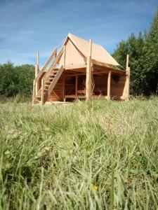 una casa de madera en un campo de hierba en Tente bivouac Élevage Girbal, en La Chapelotte
