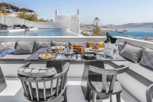 a table and chairs on a balcony with a meal at Tagoo Black Mykonos in Mýkonos City