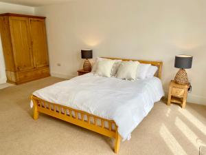 赫爾姆斯利的住宿－Rye Court Cottage - Stunning cottage in central Helmsley with parking，一间卧室配有一张大床,桌子上放着两盏灯