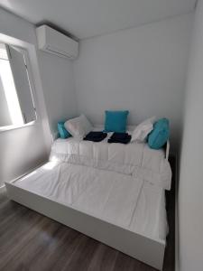a white bedroom with two beds with blue pillows at Casa Giraldo sem Pavor in Évora
