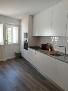 an empty kitchen with white cabinets and a sink at Casa Giraldo sem Pavor in Évora