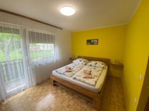 a bedroom with a bed with yellow walls and a window at Apartment Konavec in Kobarid