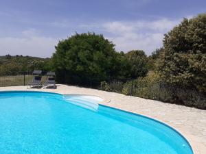 a large swimming pool with two chairs in a yard at Tiny House Belleraze in Saint-Jean-de-Minervois