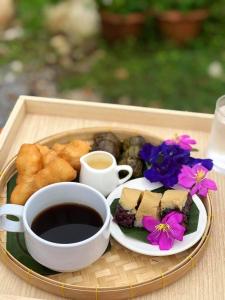 a tray of food with a cup of coffee and flowers at บ้านสวนทิวภูผาวัดเจดีย์ไอ้ไข่ in Ban Sai Liang