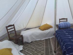 een kamer met 2 bedden en 2 stoelen in een tent bij EcoCamping d Hacadour in Mellionnec