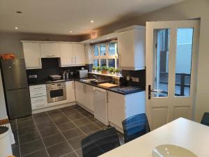 a kitchen with white cabinets and a table and chairs at Castleview Large 3 Bedroom Family House - Glenarm in Glenarm