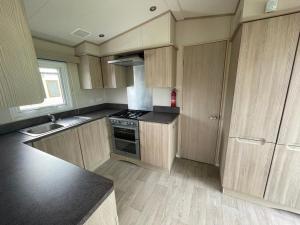 a kitchen with wooden cabinets and a stove top oven at PG177 Golden Palm Resort 8 Berth Caravan With Decking in Chapel Saint Leonards