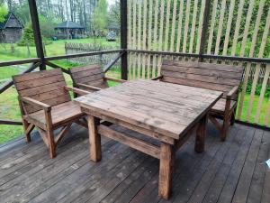 a wooden table and two chairs on a deck at Pie Andra Pitragā in Pitragutsiyeme