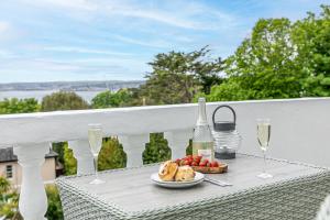 a table with a plate of food and glasses of wine at Vomero Holiday Apartments in Torquay