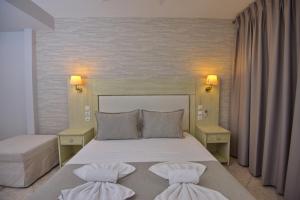 a bedroom with a large white bed with two pillows at Pension Votsi in Votsi