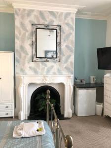 a bedroom with a fireplace with a mirror and a bed at The Mayfair Hotel in Great Yarmouth