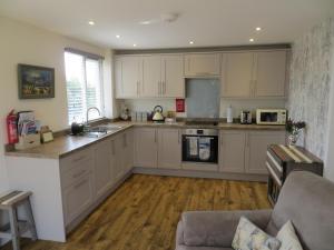 a kitchen with white cabinets and a couch in a room at Lynda's in Hunstanton