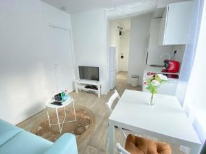a white living room with a table and a tv at Appartement Gare de Meaux - Proche Disney /Paris in Meaux