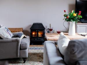 a living room with a couch and a fire place at Jasmine Cottage in Little Witcombe